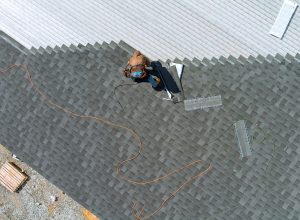 Aerial top view a asphalt shingles installation on the roof roofer is nailing asphalt shingles to roofing construction