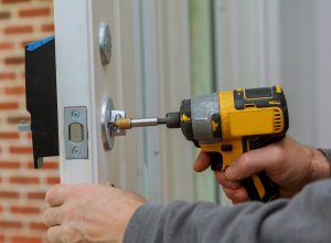 Install the door handle with a lock, Carpenter tighten the screw, using an electric drill screwdriver, close-up.